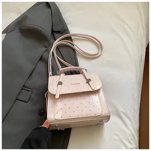 Detailansicht der hellrosa gepunkteten Handtasche mit Metallnieten auf weißem Leinen