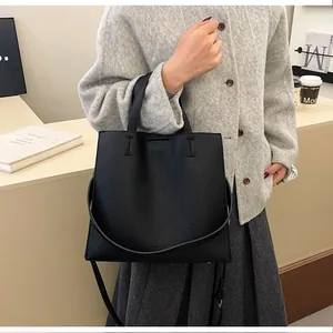 Detail of black litchi texture tote bag with crossbody strap and fine stitching
