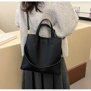 Close-up of black lychee grain leather tote bag with gold hardware and shoulder strap