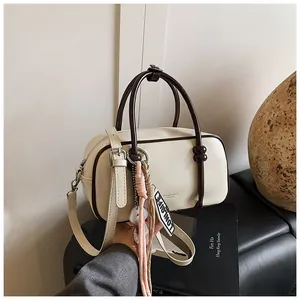 Détail du sac Boston crème avec poignées marron foncé et finitions en métal argenté