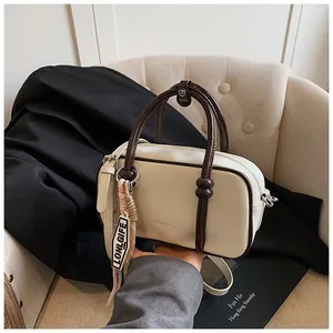 Détail du sac Boston crème avec poignées marron et étiquette ruban Lonlgife