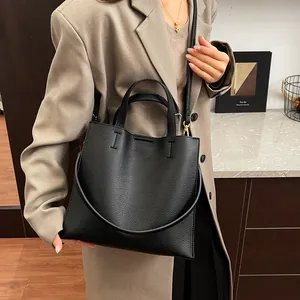 Chic black lychee grain leather tote bag with gold hardware and adjustable strap