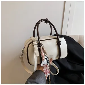 Détail du sac Boston crème avec poignées marron et un pendentif chien tendance
