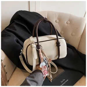 Détail du sac Boston crème avec poignées marron et pendentif chiot blanc décoratif