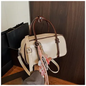 Détail du sac Boston crème avec poignées marron foncé et pendentif chiot décoratif