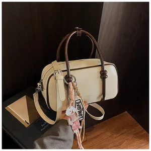 Détail du sac Boston crème et marron avec bandoulière et pendentif petit chien