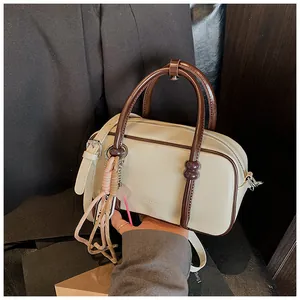 Détail du sac Boston en cuir PU crème avec poignées marron et charm tissé décoratif