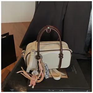 Détails du sac Boston avec fermeture éclair, anses brunes et charmant pendentif chien