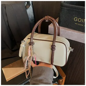Détail du sac à main Boston crème avec bordure marron et pendentifs décoratifs porte-bonheur