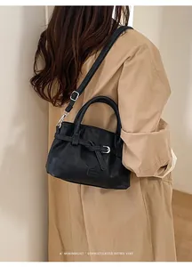 Detail of a black matte leather crossbody bucket bag with silver buckle and shoulder strap