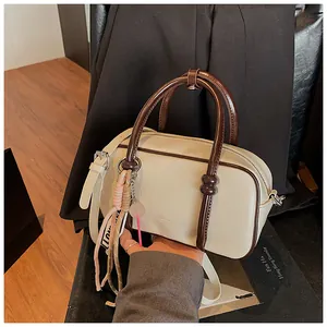 Détail du sac Boston crème avec poignées marron foncé et breloque LOVE élégante