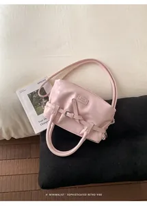 Detail view of pink minimalist leather bucket bag on soft black cushion background