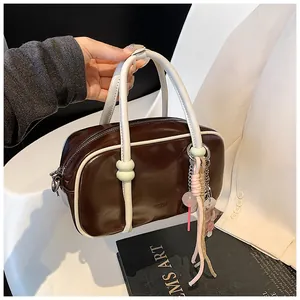 Détail du sac Boston marron et crème avec breloques d'ours mignon et pompon rose