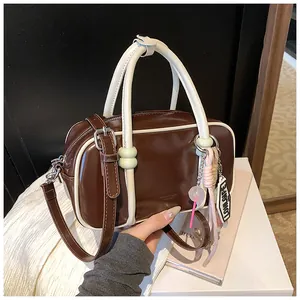 Détail du sac Boston marron foncé en cuir poli avec un charme coloré décoratif