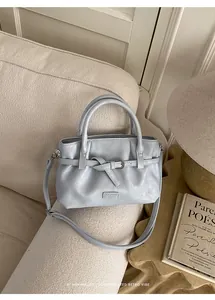 Detailed view of light blue bucket bag with metal buckle on a cozy sofa setting
