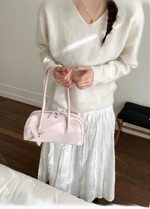 Detail of light pink Boston bag with star charm and double handles on a model