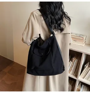 Detail of black corduroy tote bag featuring adjustable strap and front pocket