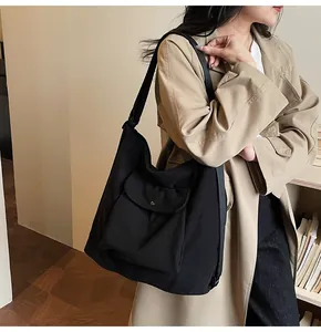 Detail of black corduroy tote bag featuring a front flap pocket and sturdy wide strap