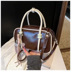 Détail du sac Boston marron rétro avec liseré crème et un pendentif sucette rose