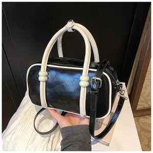 Détail du sac Boston noir et blanc brillant avec des accents verts élégants sur les poignées