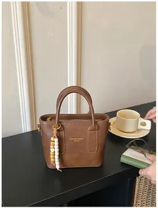 Braune Vintage-Handtasche aus Kunstleder mit Perlenanhänger und goldenem Schriftzug