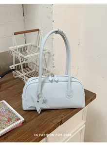 Detail of light blue leather shoulder bag with star charm and dual zippers