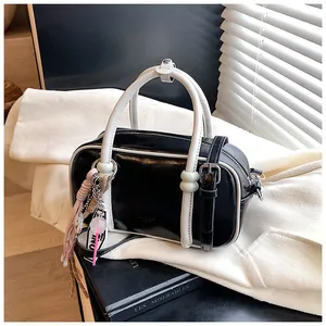 Détails du sac Boston noir et blanc au fini brillant avec charm rose sur livres
