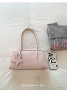 Close-up of a pink rectangular shoulder bag with star charm on textured white linen