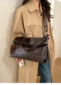 Detail of dark brown tote bag with vintage texture and wooden bead charm on shoulder strap