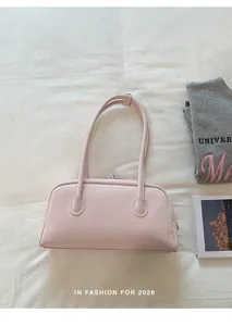 Close-up of light pink PU leather bowling bag on white textured fabric with modern props