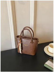 Nahaufnahme der braunen PU-Lederhandtasche mit Vintage-Textur und Holzperlen-Anhänger