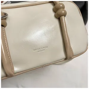 Détail du sac Boston montrant la texture du cuir beige et le logo embossé avec soin