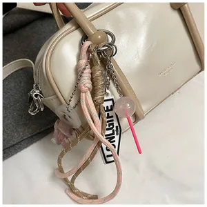 Détail d'un porte-clés tressé avec breloque chien et pendentif sucette sur sac en cuir
