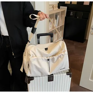 Detail einer großen cremefarbenen Segeltuchtasche mit schwarzem Logo und Schultergurt