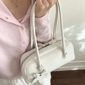 Minimalist white leather shoulder bag with star charm worn by a fashion model