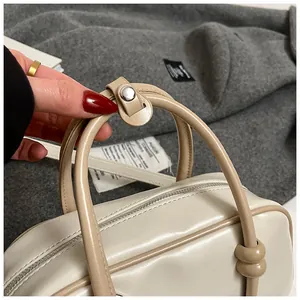 Détail de la poignée du sac Boston en cuir kaki avec bouton en métal argenté brillant