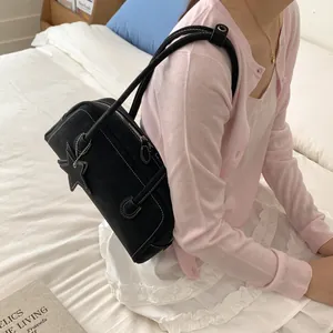 Black leather shoulder bag with white contrast stitching and star charm for daily use