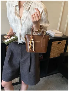 Braune Lederhandtasche mit bunten Holzperlenquasten und Fashion-Logo-Branding