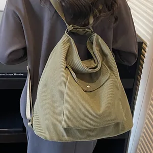 Large olive green corduroy tote bag with adjustable metal buckle shown on shoulder