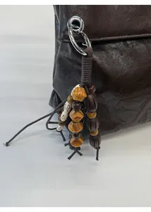 Detail of dark brown leather tote featuring a vintage style wooden bead tassel accessory