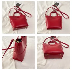 Detail view of red glossy leather handbag showing golden hardware and bottom rivets