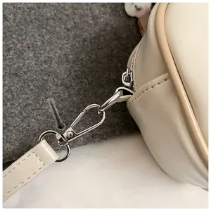 Détail du sac Boston en cuir PU crème avec crochets métalliques et bordure contrastée