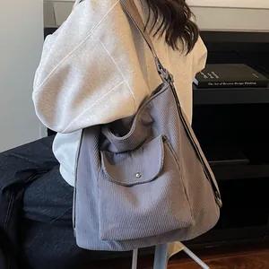 Large dark grey corduroy tote bag with front flap pocket shown on a model