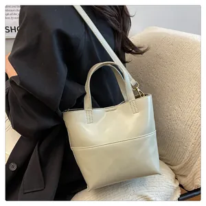 Minimalist cream tote bag with fine stitching shown from the back on a model