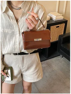 Detailed view of brown PU leather handbag with silver twist lock and structured top handle