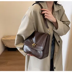 Close-up of a vintage dark brown shoulder bag with a gold floral hardware buckle