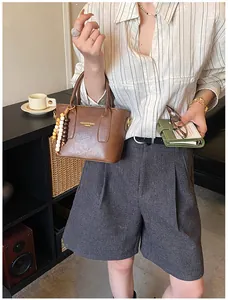 Detail der braunen Retro-Eimertasche aus Leder mit Holzperlenanhänger und Modedruck