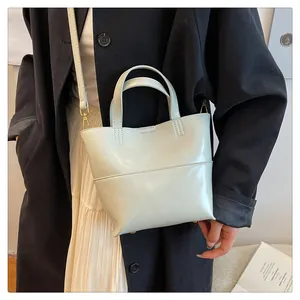 Detail showing the adjustable shoulder strap with gold metal hooks on a cream tote bag