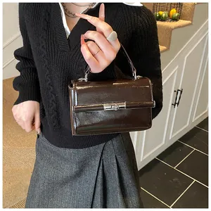 Macro detail of dark brown patent leather handbag with silver metallic lock closure