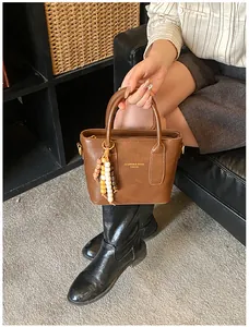 Nahaufnahme einer braunen Vintage-Tasche mit Perlenanhänger auf einem Ledersofa